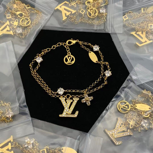 Dazzling Gold Tone Layered Chain Bracelet with Crystal Initials and Floral Charm